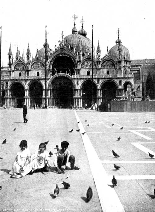 Children feeding Pigeons in the Piazza of St. Mark, Venice. Notice the three flag-poles, and the bronze horses over the central
doorway of the Cathedral.

